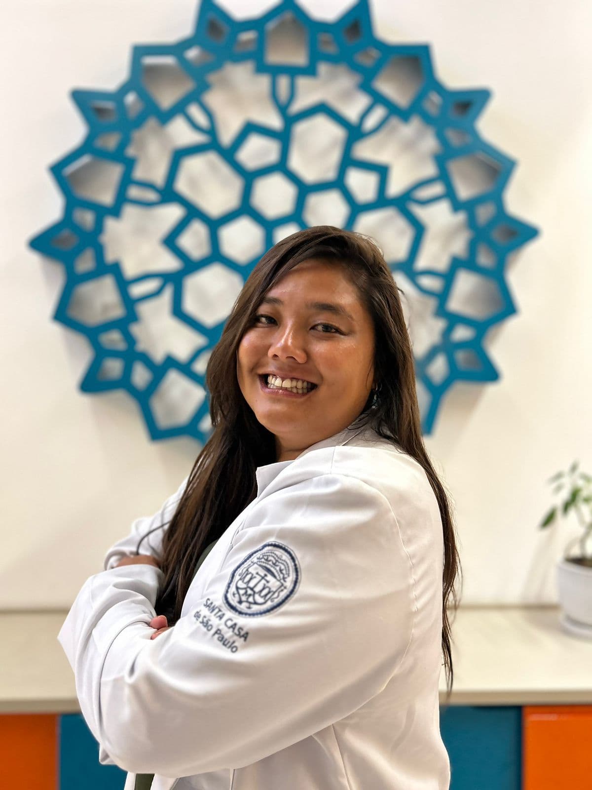 Retrato da Dra. Nadia Mie no consultório, com a mandala azul ao fundo